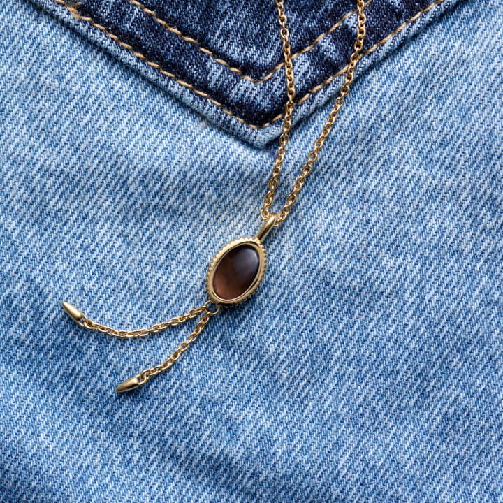 Image of a Bolo Pendant Necklace on denim.