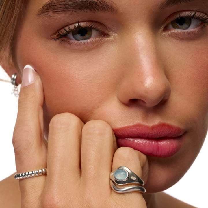 A model wearing the Harvest Signet Ring in aquamarine, the Harvest Stacking Ring, and the Rind Ring.
